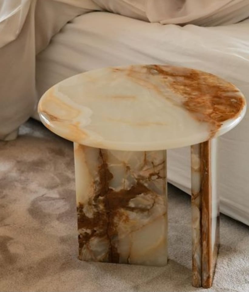 Mesa de cabeceira orgânica em pedra bege com veios caramelo.